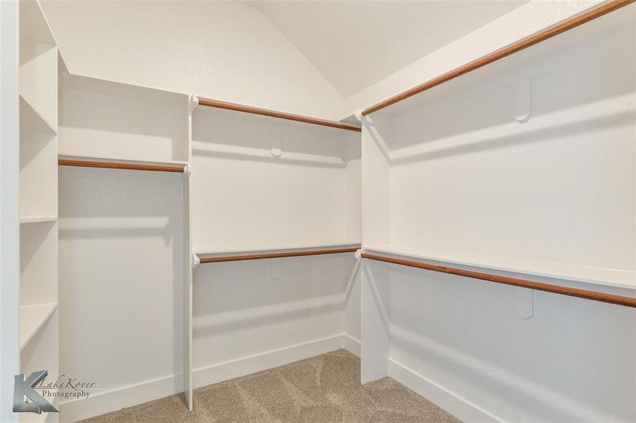 Walk in closet with light colored carpet and vaulted ceiling