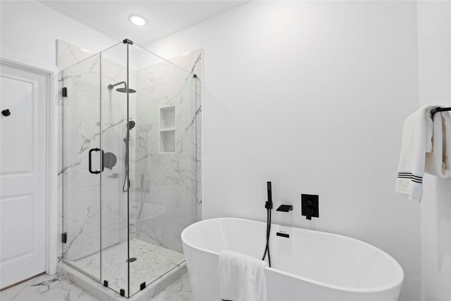 The primary bath blends luxury and practicality with a frameless glass shower and a freestanding soaking tub set against marble-look tile—spa-like design that stays within reach. The primary bath blends luxury and practicality with a frameless glass shower and a freestanding soaking tub set against marble-look tile—spa-like design that stays within reach.