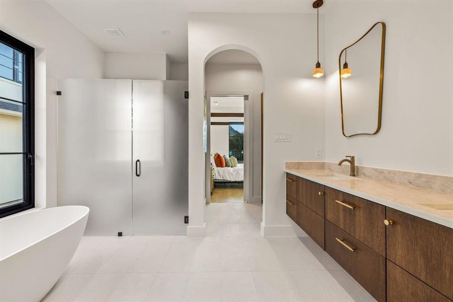 Ensuite bathroom featuring double vanity, a freestanding bath, a shower stall, and light tile patterned flooring Ensuite bathroom featuring double vanity, a freestanding bath, a shower stall, and light tile patterned flooring