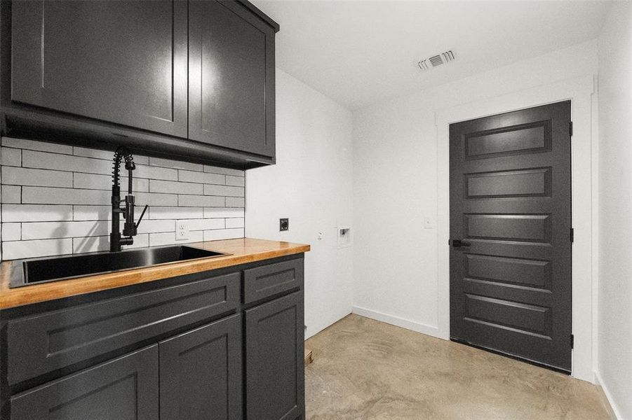 Laundry room featuring washer hookup, unfinished concrete floors, and cabinet space