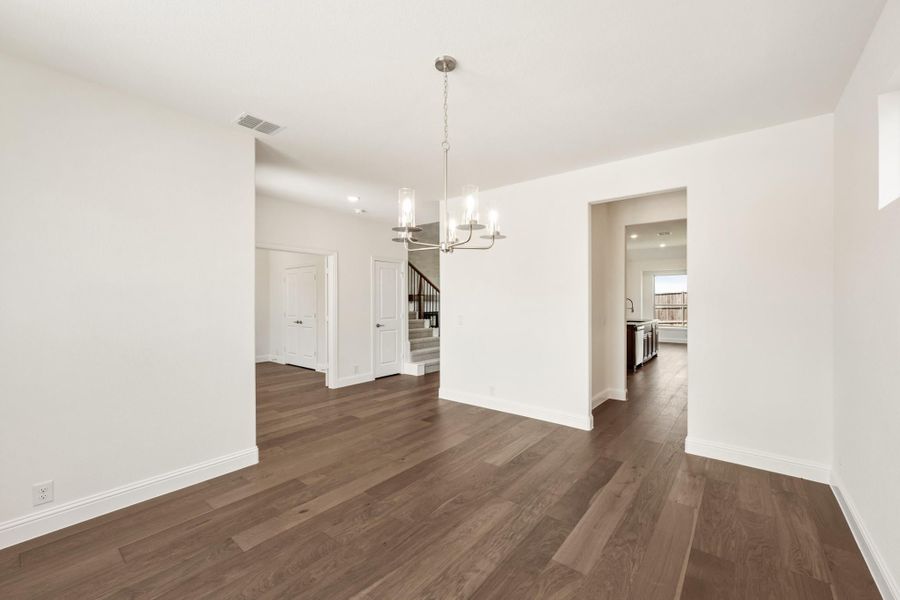 Empty dining room with dark hardwood floors, white walls, and a modern chandelier overhead Empty dining room with dark hardwood floors, white walls, and a modern chandelier overhead