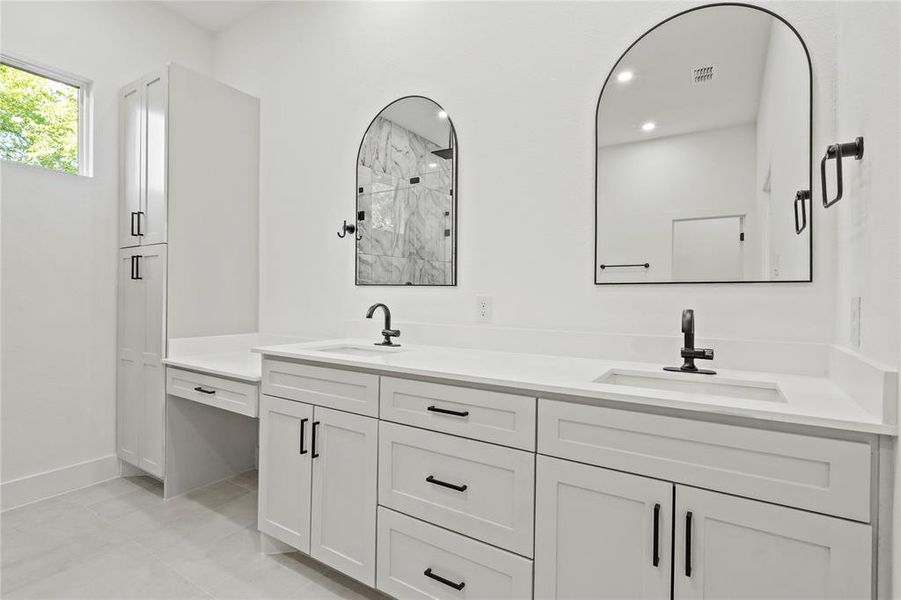 Bathroom featuring double vanity, a marble finish shower, and light tile patterned floors
