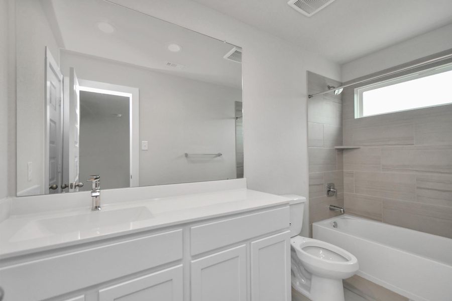 Bath/shower combo surrounded by tasteful tile in this secondary bath. Sample photo of completed home with similar floor plan. Actual colors and selections may vary.