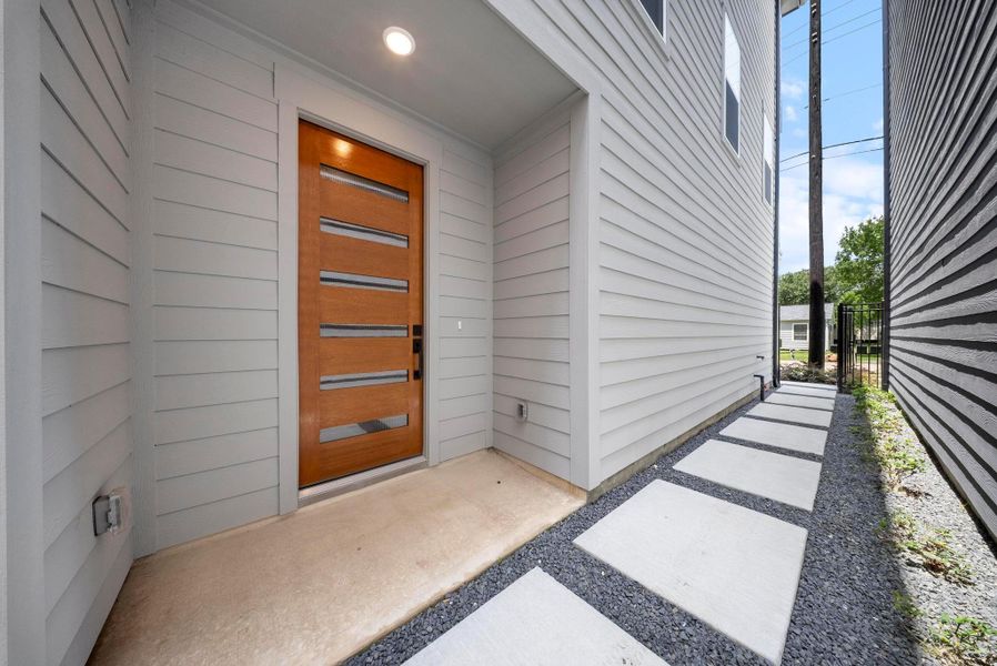 Welcome home to a modern entrance featuring sleek design and a stylish wooden door, setting the tone for contemporary living.