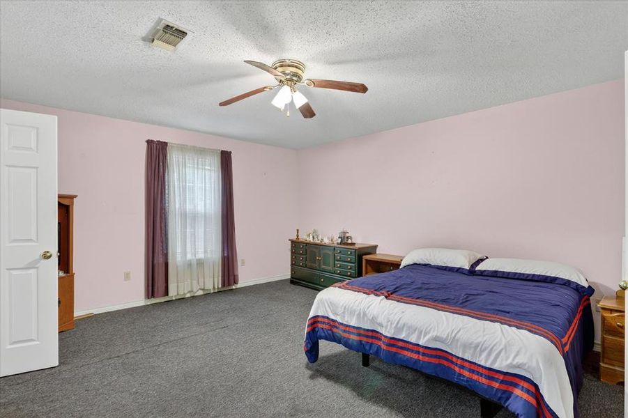Spacious bedroom featuring neutral carpeting, and ceiling fan