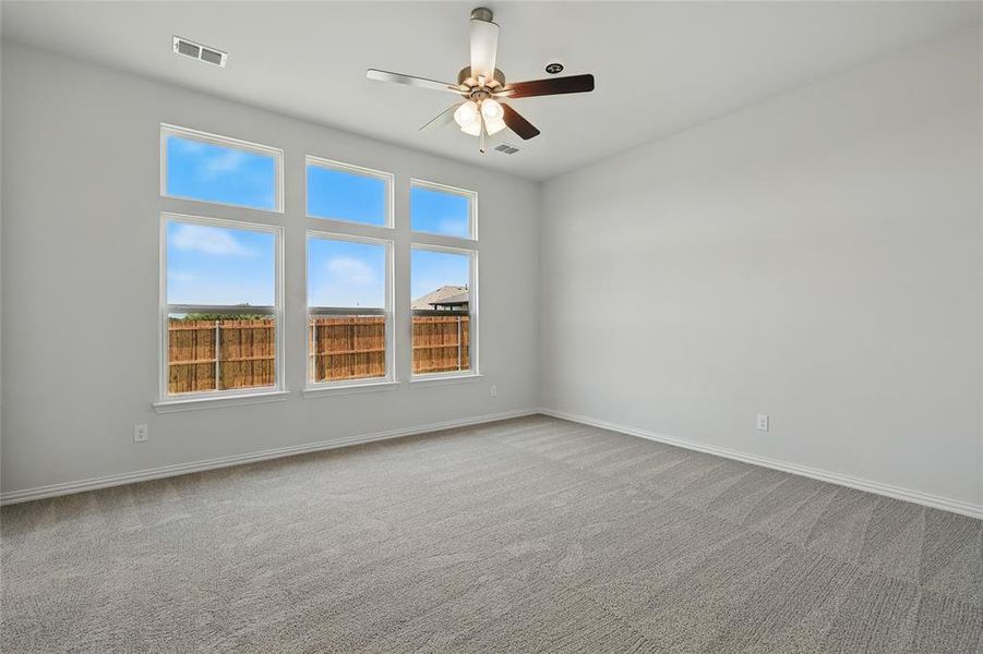 Empty room with ceiling fan and light carpet