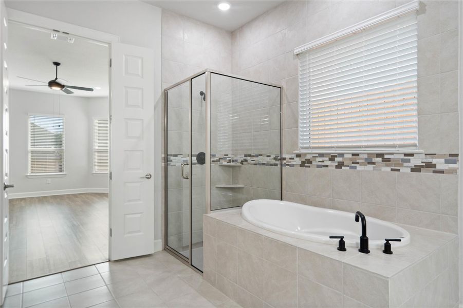 An inviting soaking tub pairs with a glass-enclosed shower surrounded by elegant tile walls.