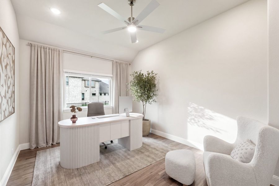 Home office with white oval desk, ceiling fan, hardwood floors, and a window with neutral drapes