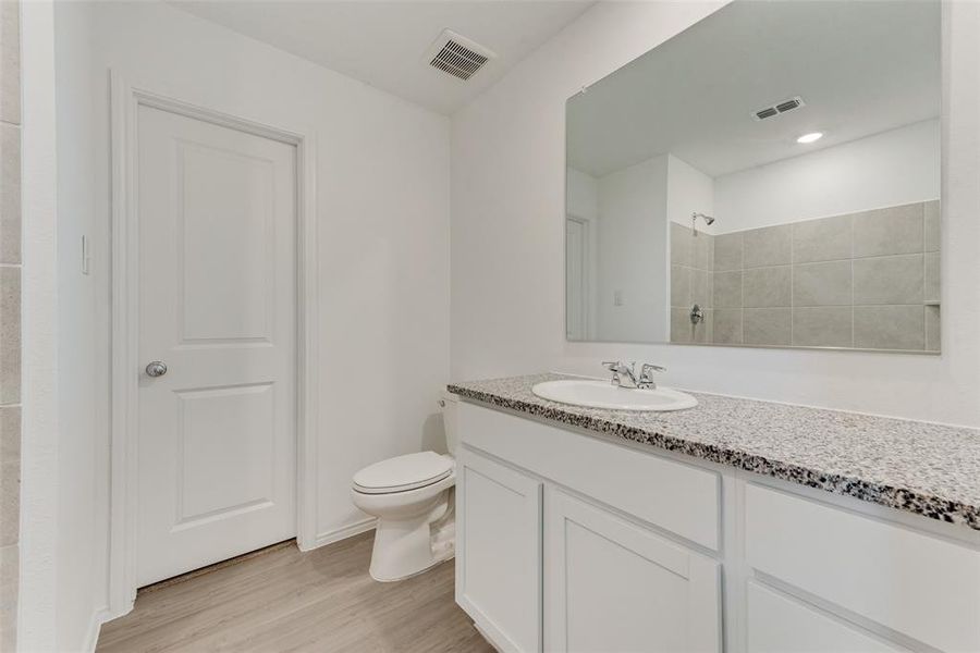 Bathroom with vanity, a tile shower, hardwood / wood-style flooring, and toilet