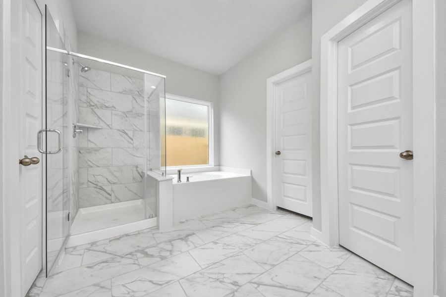 Escape to a spa-like oasis in this primary bathroom. Enjoy a walk-in shower with tile surround, a separate garden tub with custom detailing, and an elegant vanity featuring light countertops, modern hardware, and beautiful vanity lights. Experience luxury and relaxation in every detail.