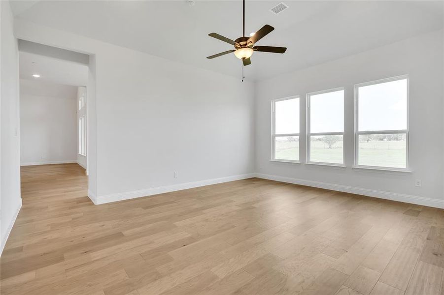 Empty room with ceiling fan and light hardwood / wood-style floors