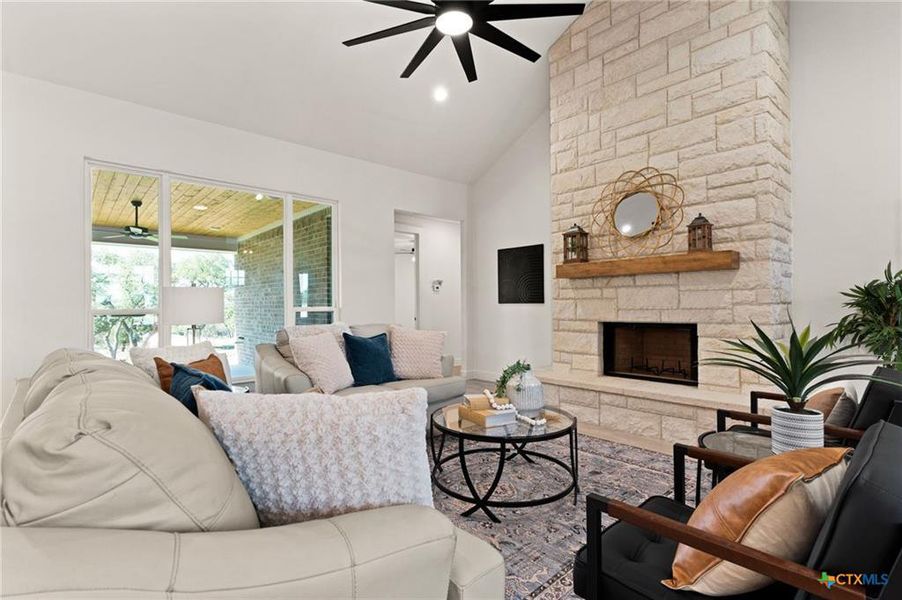 Living room featuring ceiling fan, high vaulted ceiling, a fireplace, and recessed lighting