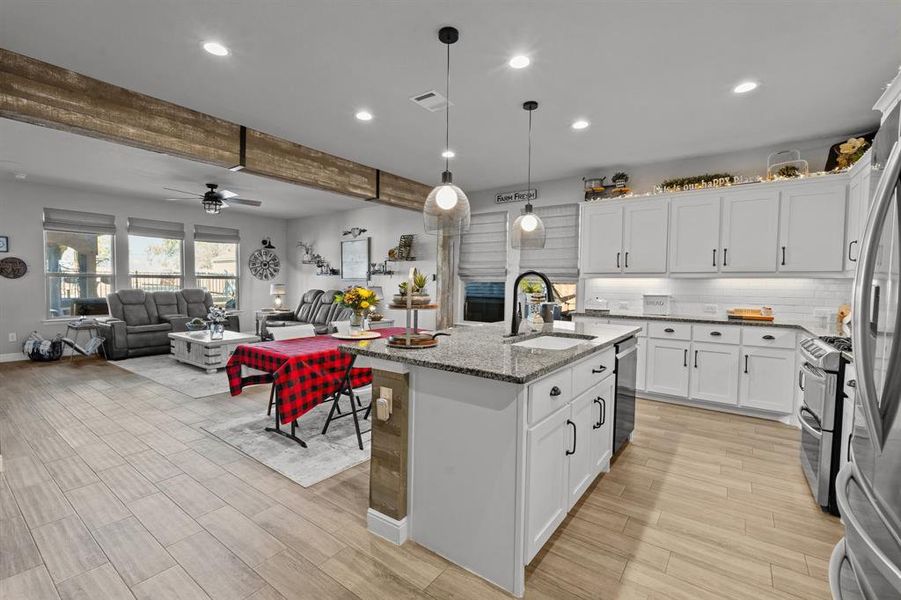 Kitchen with sink, ceiling fan, an island with sink, white cabinetry, and stainless steel appliances