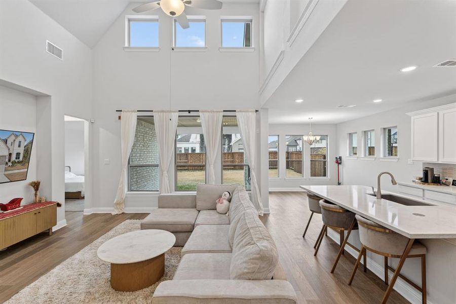 Living room featuring plenty of natural light, ceiling fan, light wood-type flooring, and high vaulted ceiling Living room featuring plenty of natural light, ceiling fan, light wood-type flooring, and high vaulted ceiling