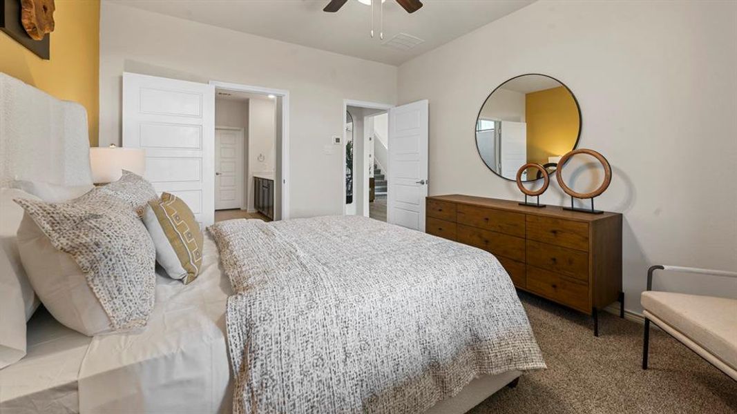 Carpeted bedroom featuring connected bathroom and a ceiling fan Carpeted bedroom featuring connected bathroom and a ceiling fan