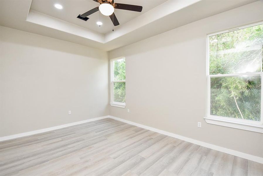 Primary Bedroom with Tray Ceiling, LED lighting, and Ceiling Fan