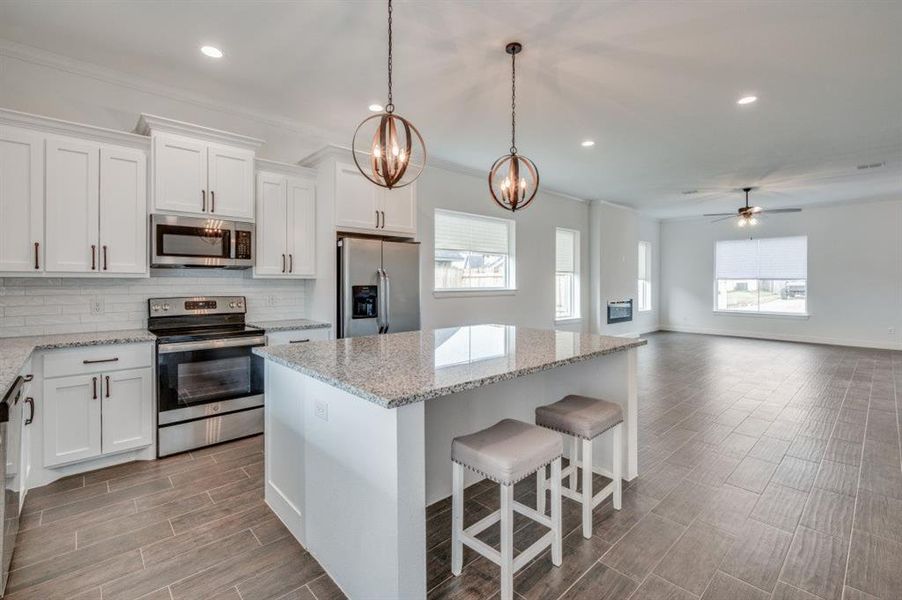 Kitchen with a center island, white cabinets, ceiling fan with notable chandelier, and appliances with stainless steel finishes