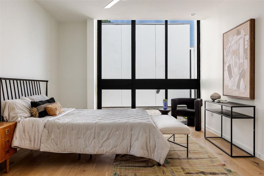 Bedroom featuring expansive windows and wood finished floors