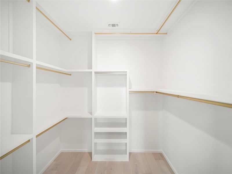 Walk in closet with light wood finished floors