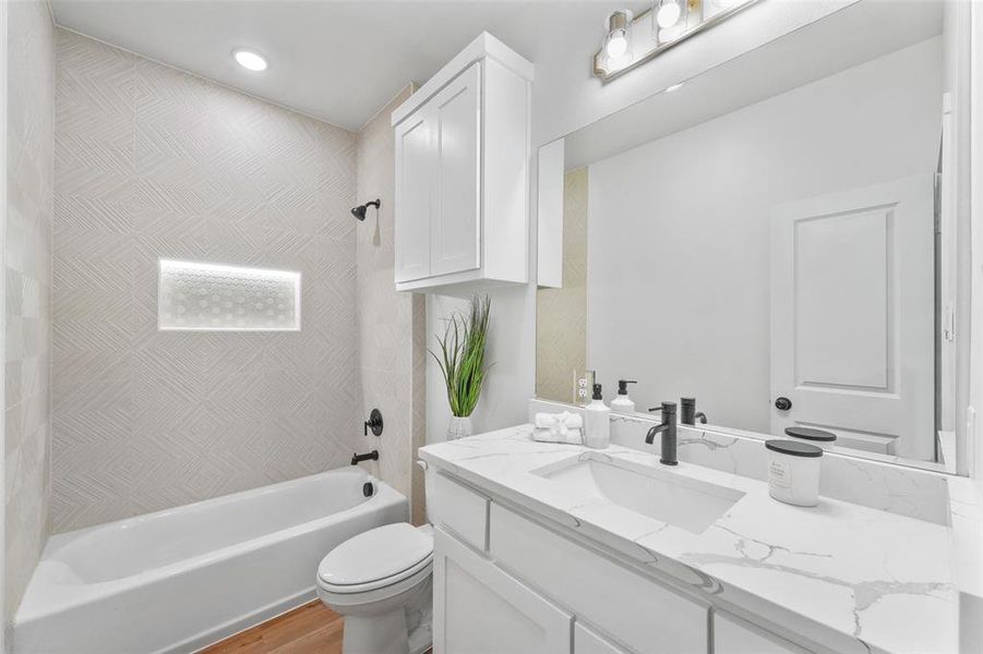 Bathroom featuring a white vanity with a rectangular undermount sink, a white countertop with grey veining, and a matte black faucet Bathroom featuring a white vanity with a rectangular undermount sink, a white countertop with grey veining, and a matte black faucet