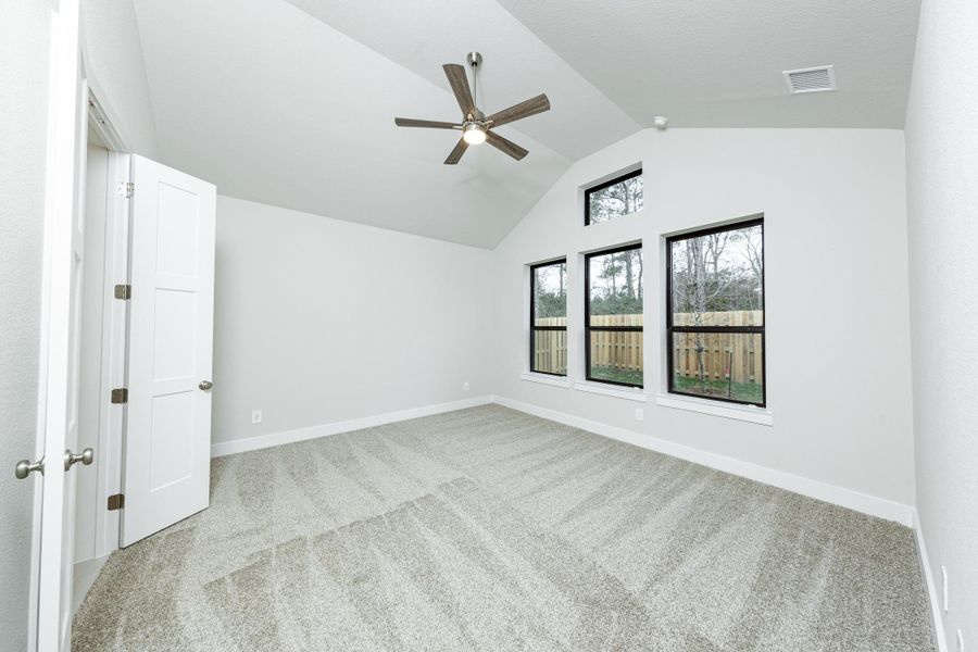 Relax and unwind after a long day in this impressive primary suite! This generously sized room offers plush carpeting, neutral-toned paint, high ceilings with a ceiling fan, and large windows for added comfort and tranquility.