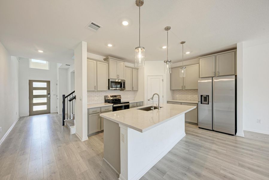 A well-appointed kitchen features a large island and contemporary fixtures, seamlessly connecting to an open living area.
