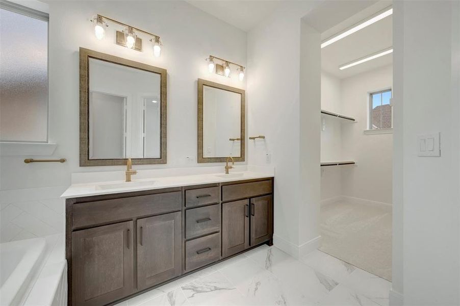 Dual vanity featuring dark wood-finish cabinetry, white countertops, and gold-toned fixtures