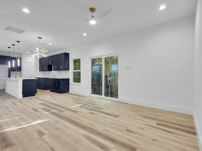 Unfurnished living room with ceiling fan with notable chandelier, light hardwood / wood-style floors, and sink