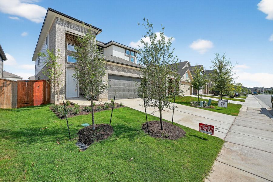 View of front facade featuring a front lawn, concrete driveway, brick siding, and a residential view View of front facade featuring a front lawn, concrete driveway, brick siding, and a residential view