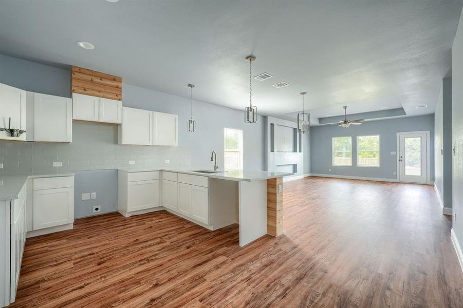 Kitchen featuring white cabinets, hanging light fixtures, tasteful backsplash, and light wood-type flooring