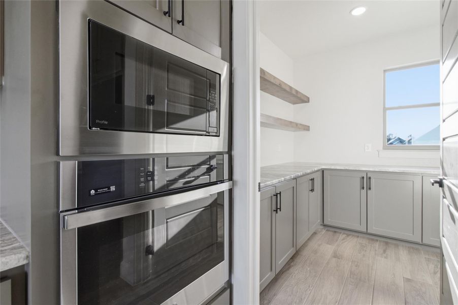 Seamlessly integrated stainless steel appliances complement sleek cabinetry and marble countertops in this well-appointed pantry. Seamlessly integrated stainless steel appliances complement sleek cabinetry and marble countertops in this well-appointed pantry.