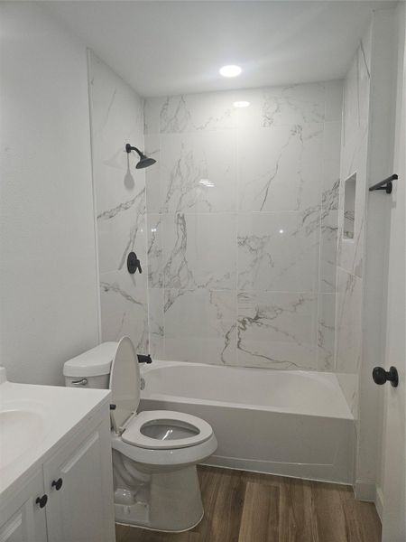 Bathroom with vanity, shower / tub combination, toilet, and wood finished floors