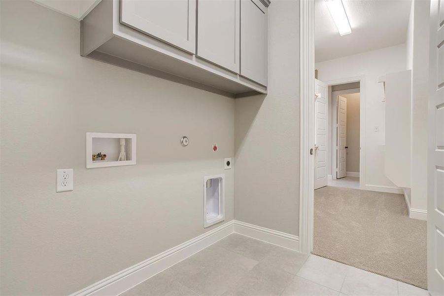 Washroom with electric dryer hookup, washer hookup, cabinets, hookup for a gas dryer, and light tile patterned floors