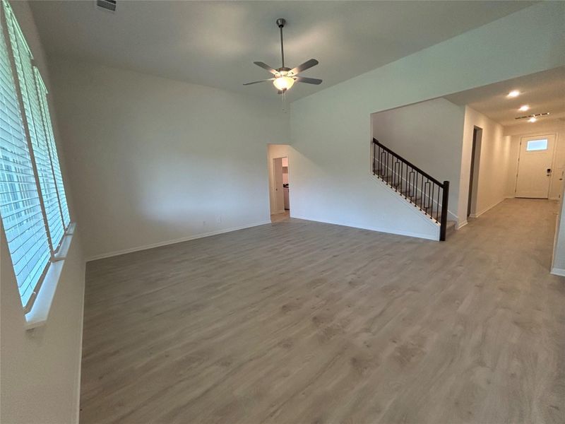 Unfurnished living room featuring wood finished floors, stairway, and ceiling fan Unfurnished living room featuring wood finished floors, stairway, and ceiling fan