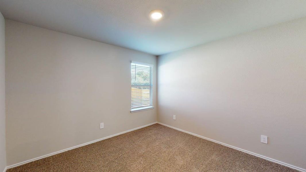 A well-lit bedroom with plush carpeting and a bright window offering natural illumination.