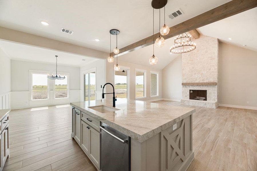 Kitchen featuring suspended lighting, open floor plan, light wood-style flooring, a fireplace, and dishwasher