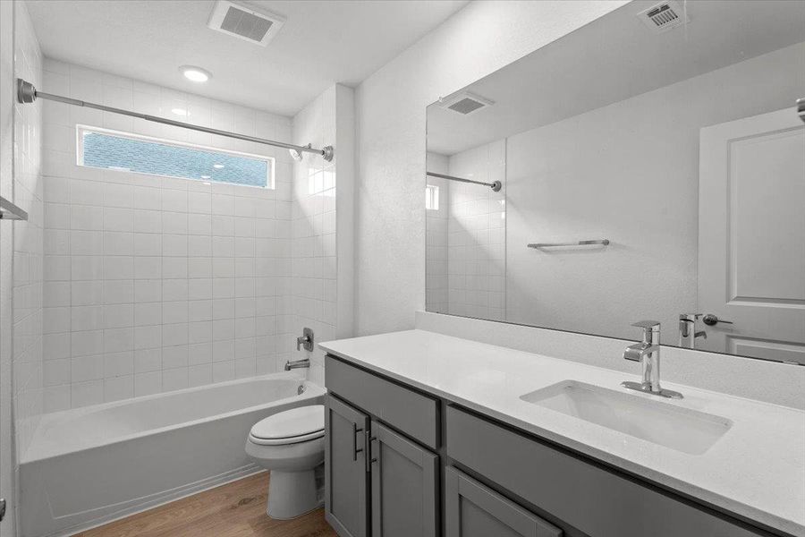 A well-lit bathroom features a spacious vanity and pristine tiled shower.