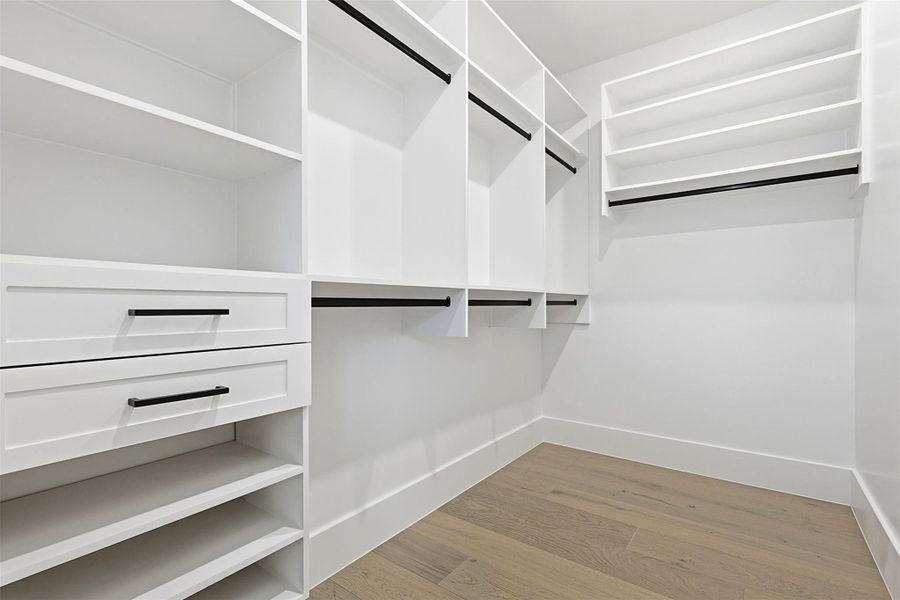 The walk-in closet is fitted with a custom white storage system including drawers, shelving, and hanging rods.