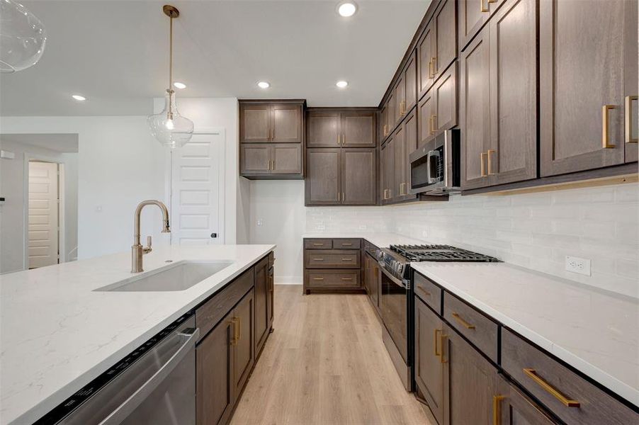 Modern kitchen featuring an expansive center island with an undermount sink and brushed brass faucet