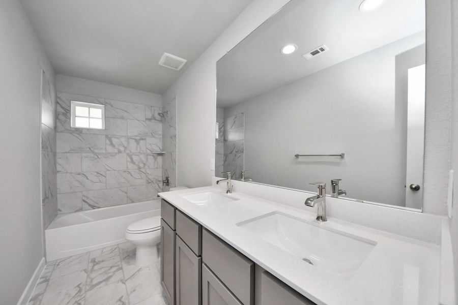 Secondary bath features tile flooring, bath/shower combo with tile surround, light stained wood cabinets, beautiful light countertop. Secondary bath features tile flooring, bath/shower combo with tile surround, light stained wood cabinets, beautiful light countertop.