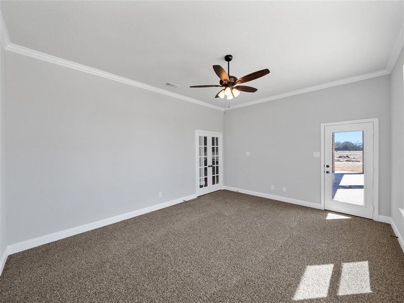 Prior listing photo. Property remains accurate - Empty room with ceiling fan, dark colored carpet, and crown molding
