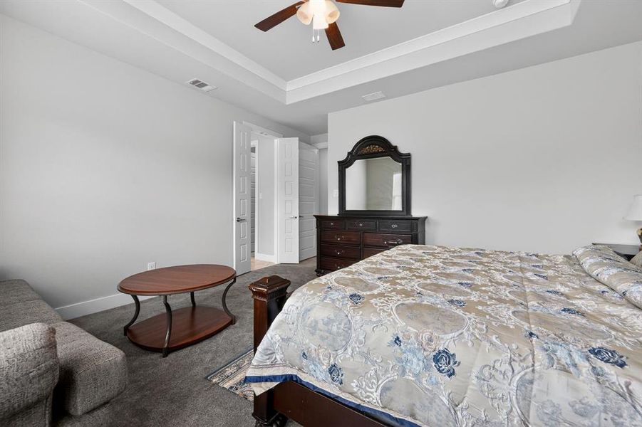 Bedroom featuring a tray ceiling with a ceiling fan, light gray walls, and carpeted flooring