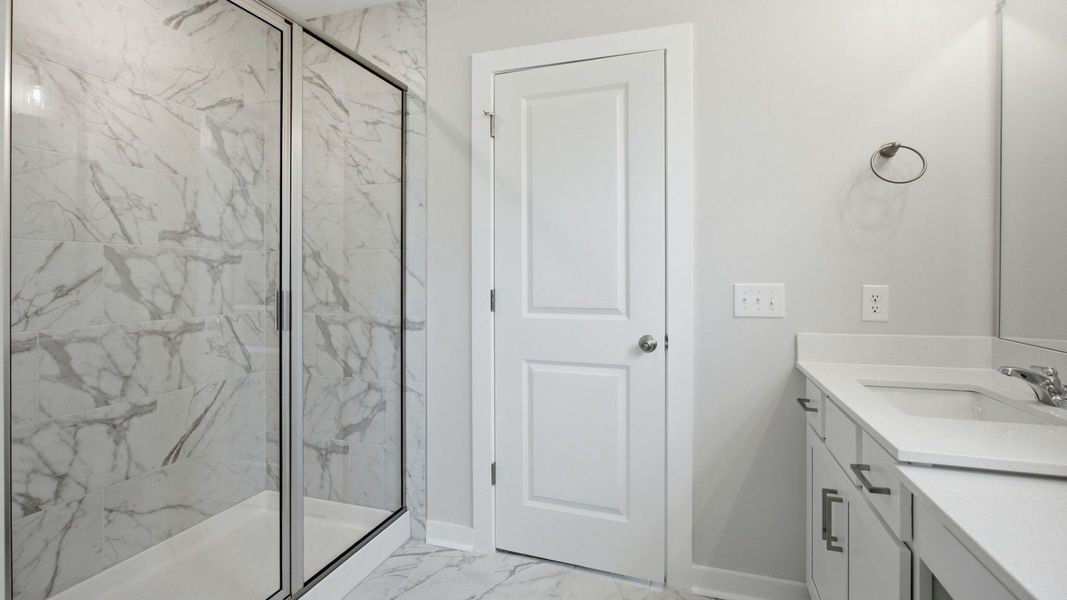 Bathroom with glass enclosed tile shower leading to primary suite Bathroom with glass enclosed tile shower leading to primary suite