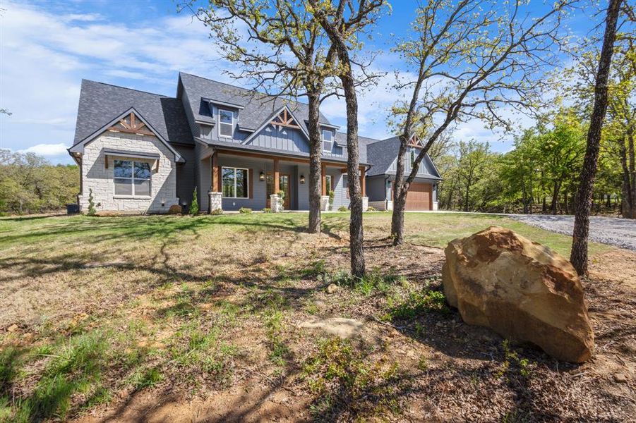 View of front of property featuring a shingled roof, a porch, a front yard, and board and batten siding