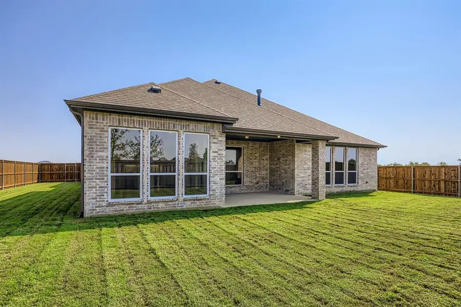 Rear view of house with a fenced backyard, a patio, brick siding, and a shingled roof