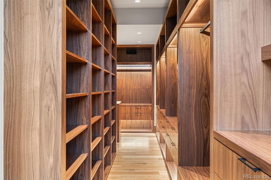 Expansive walk-in closet offers custom walnut built-in cabinetry