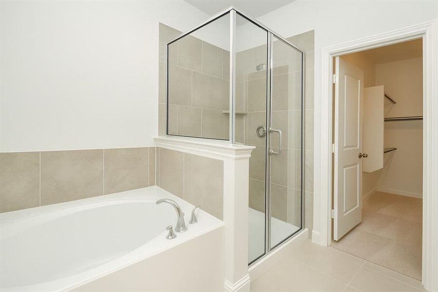 Full bath with a garden tub, tile patterned flooring, a shower stall, and a walk in closet Full bath with a garden tub, tile patterned flooring, a shower stall, and a walk in closet