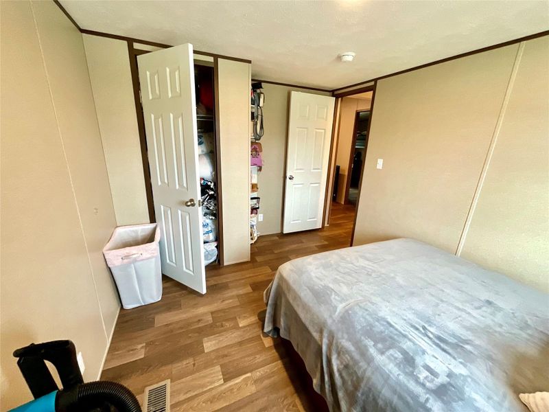 Interior room featuring wood-finish flooring, light-toned wall paneling, and white trim throughout