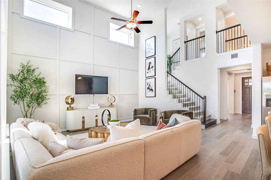 The spacious living room features high ceilings with large windows, providing ample natural light.The open staircase leads to an upper leve create a welcoming and elegant space. The spacious living room features high ceilings with large windows, providing ample natural light.The open staircase leads to an upper leve create a welcoming and elegant space.