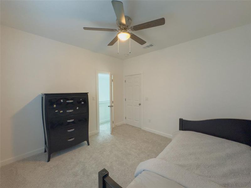 Bedroom with ceiling fan and light colored carpet